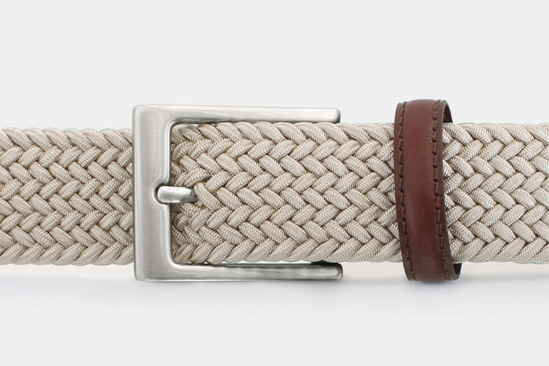 Closeup of men’s beige slim elastic woven belt with silver solid brass buckle. Handmade in Italy.