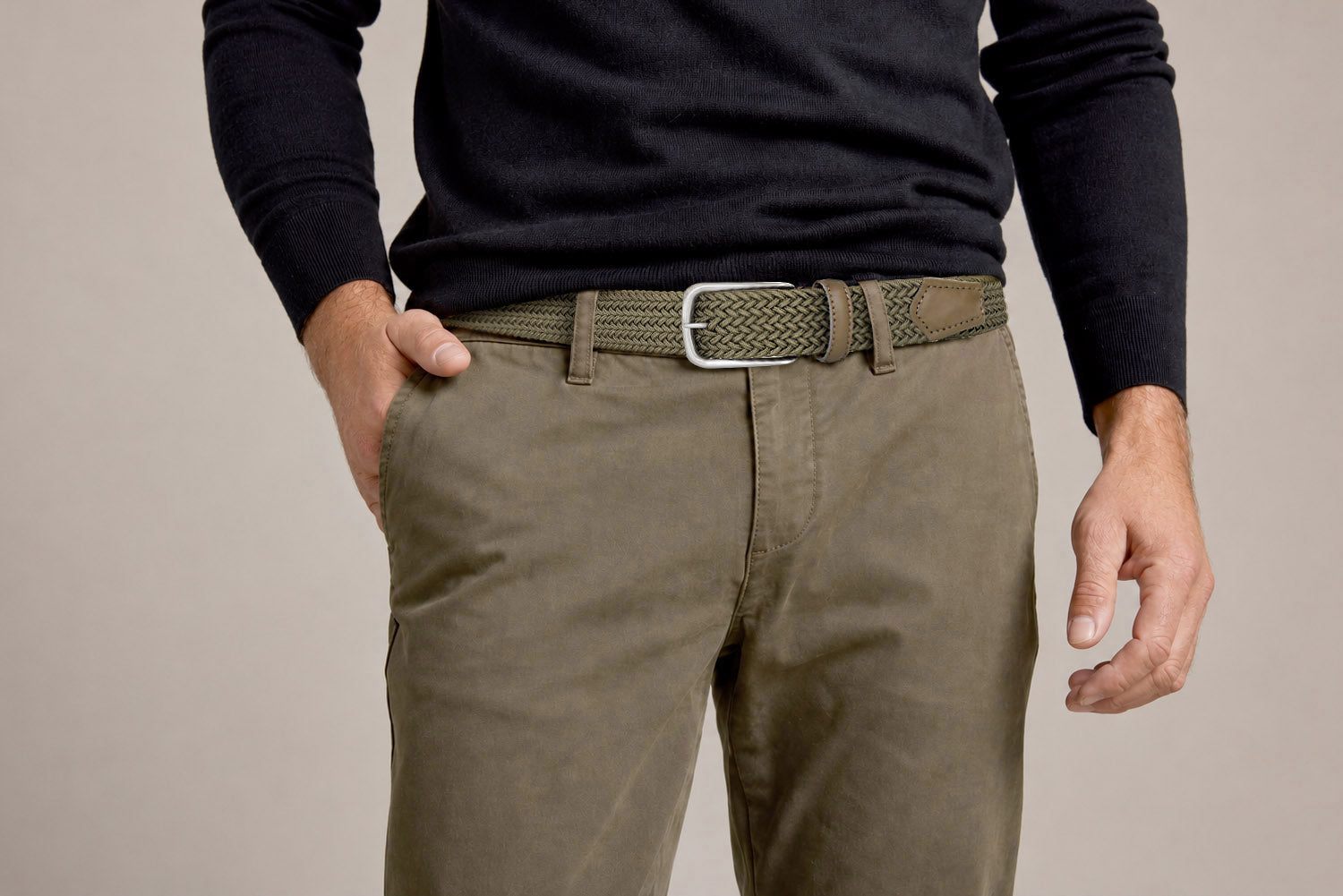 Olive woven stretch belt with silver buckle worn with olive chinos and black knit sweater