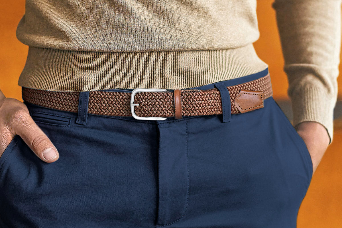 Man wearing a brown elastic belt with silver buckle, paired with navy chinos and beige jersey