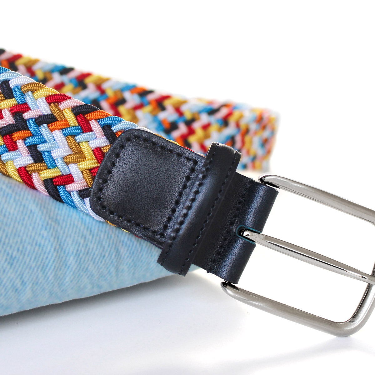 Closeup of men’s multicolour elastic woven belt with silver buckle. Handmade in Italy.