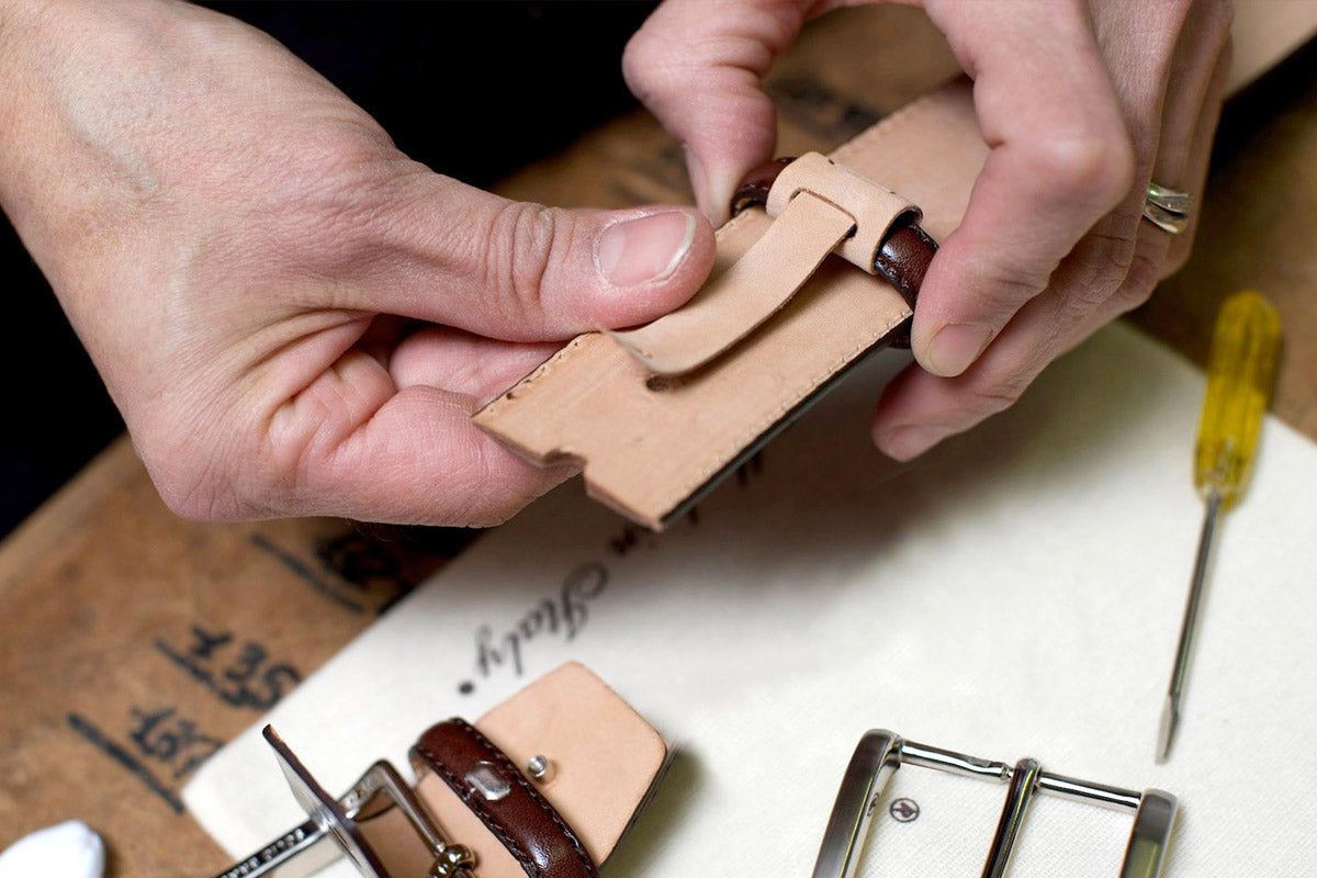 Hands assembling a leather belt with natural components, highlighting sustainable production and a lower carbon footprint.