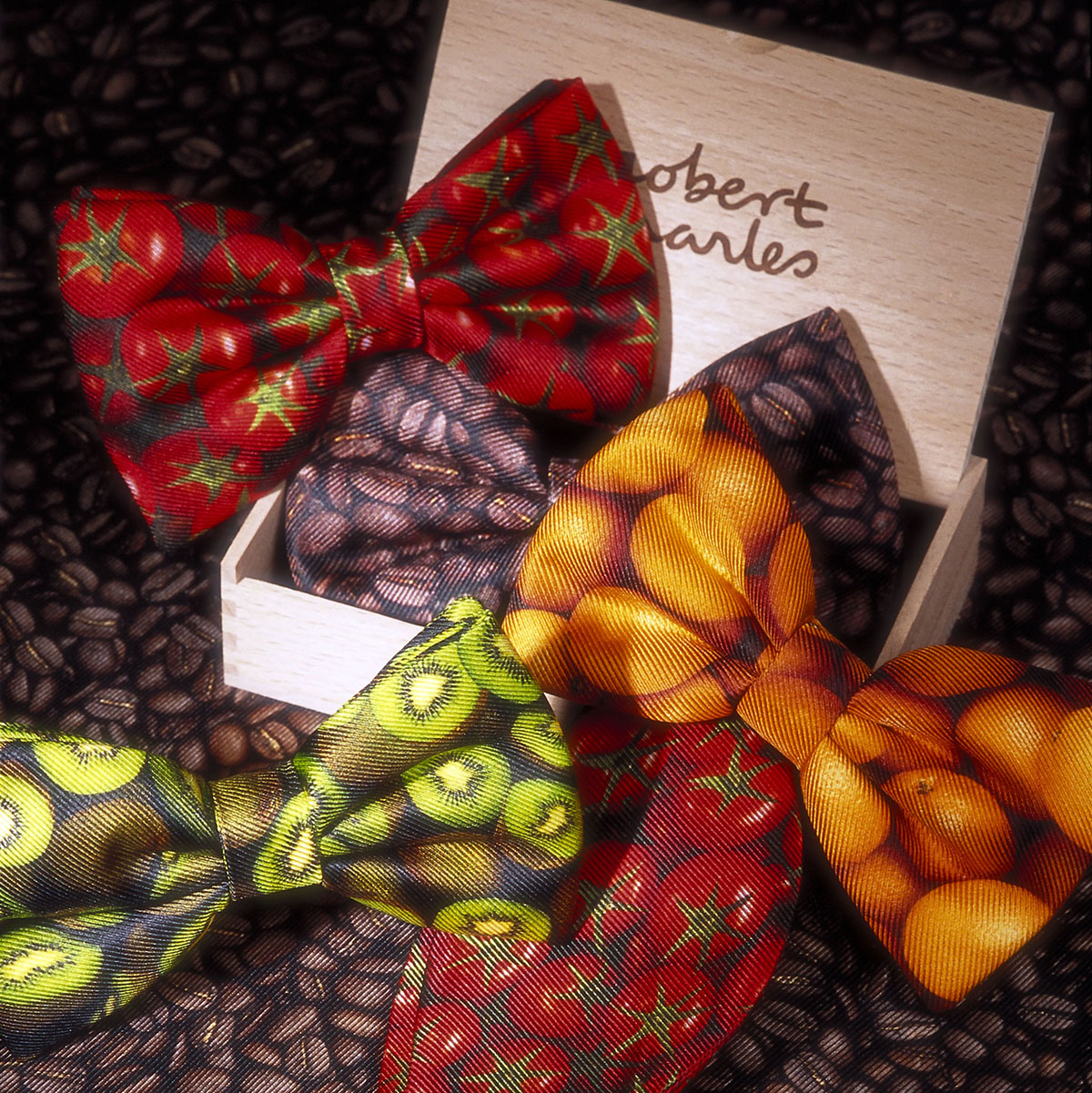 Collection of printed silk bow ties with a wooden Robert Charles gift box. Colourful designs such as Kiwfruit, Orange, Tomato and Coffee beans.