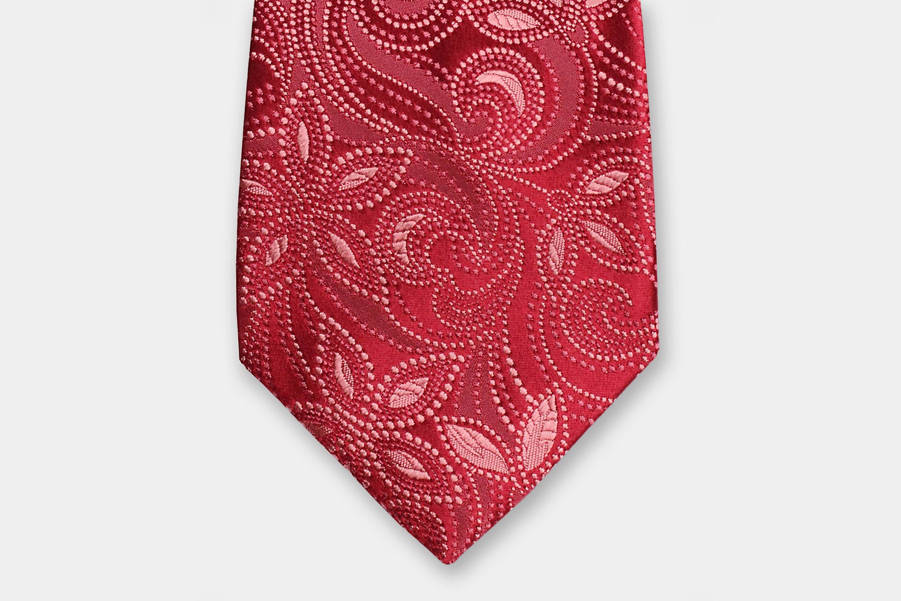 Close-up of a Robert Charles pink silk tie with a paisly design showcasing the artisan Italian intricate weave.