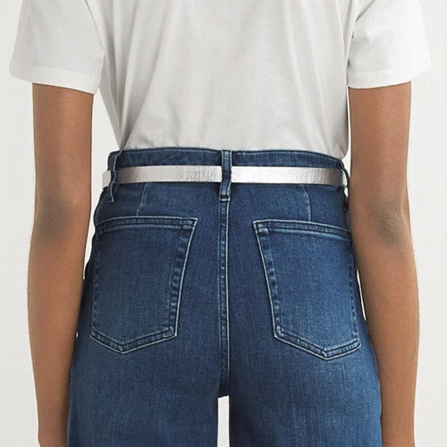 Women wearing a silver metallic grained Italian leather belt with white Shirt and blue jeans.
