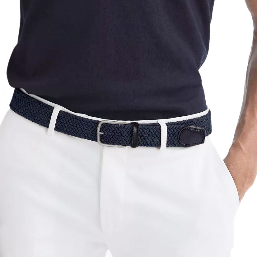 Man wearing a navy braided elastic belt with silver buckle, paired with white chinos and a navy polo