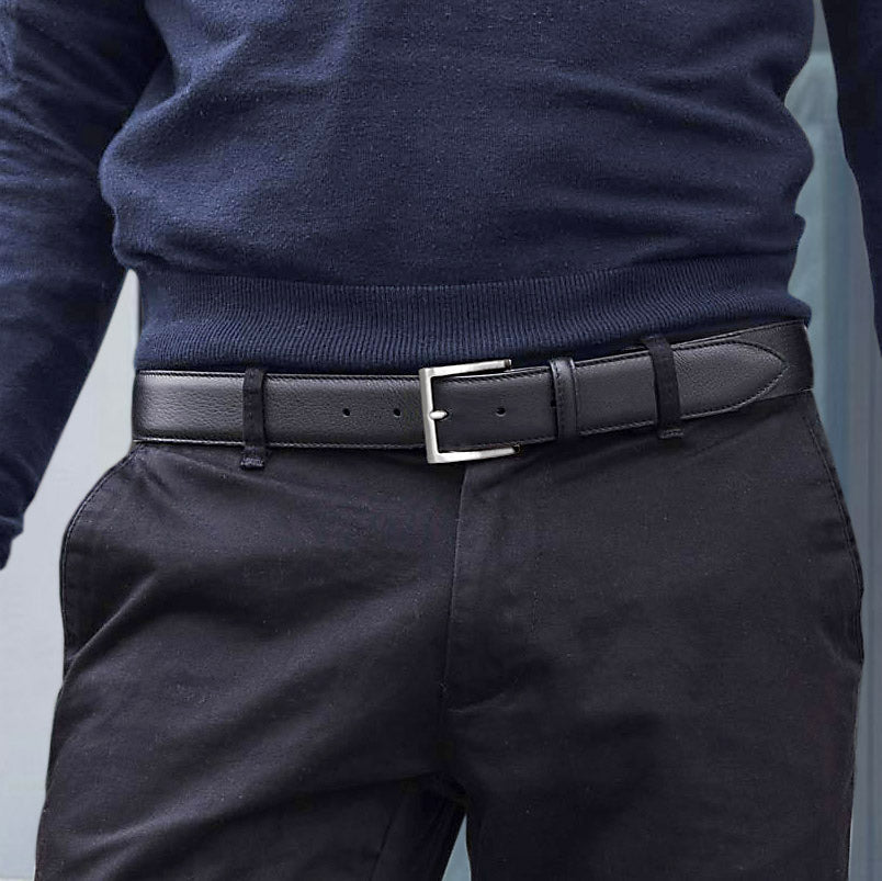Man wearing a black grained belt with silver buckle, paired with black jeans and a navy jersey