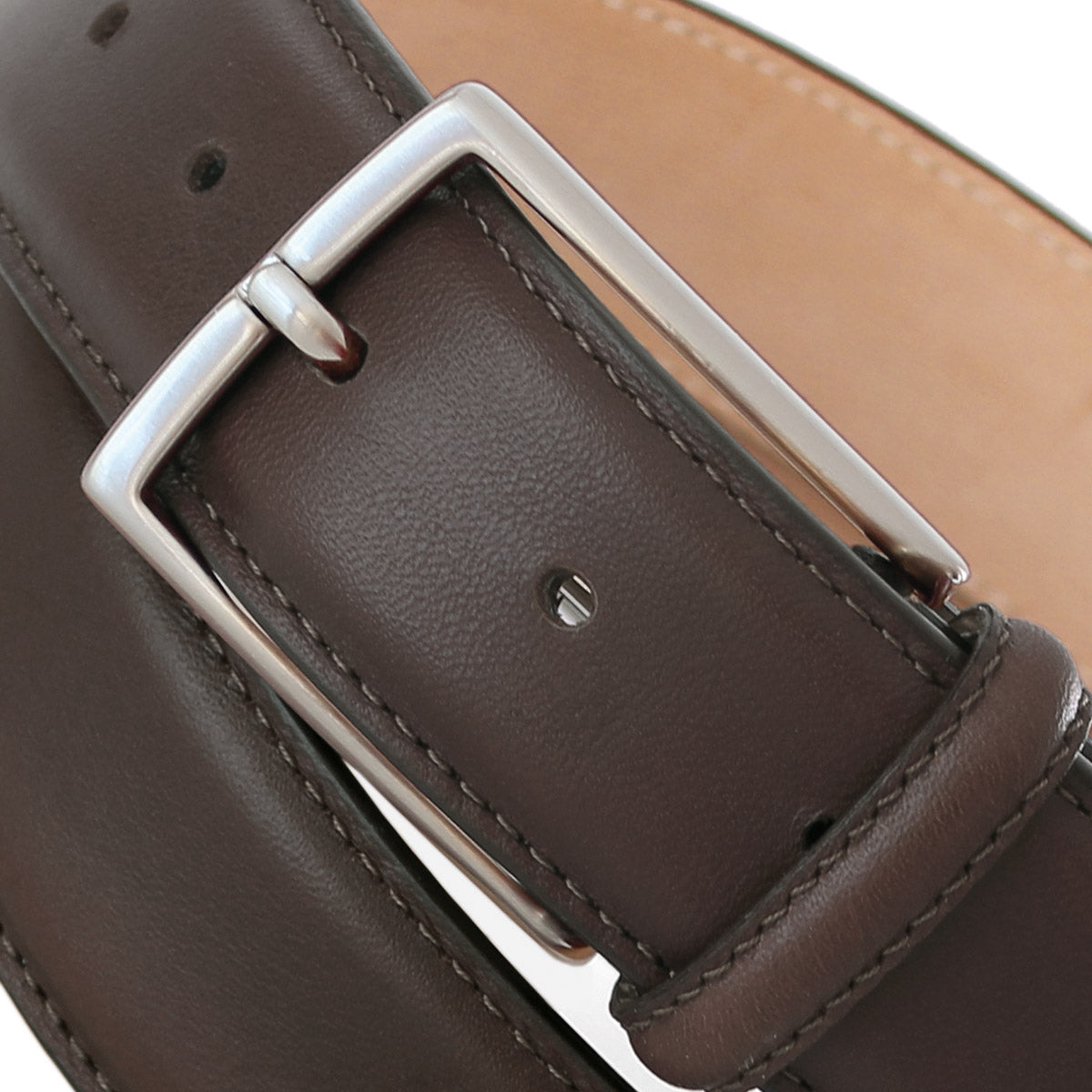 Close-up of a brown calfskin Italian leather belt with a classic solid brass buckle and stitched edge finish.
