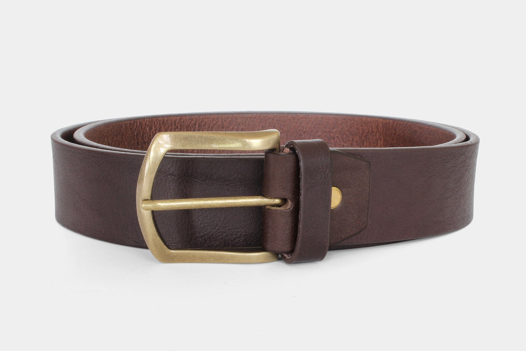 Close-up of brown Italian solid hide leather jeans belt with gold brass buckle. Raw cut and vegetable tanned.