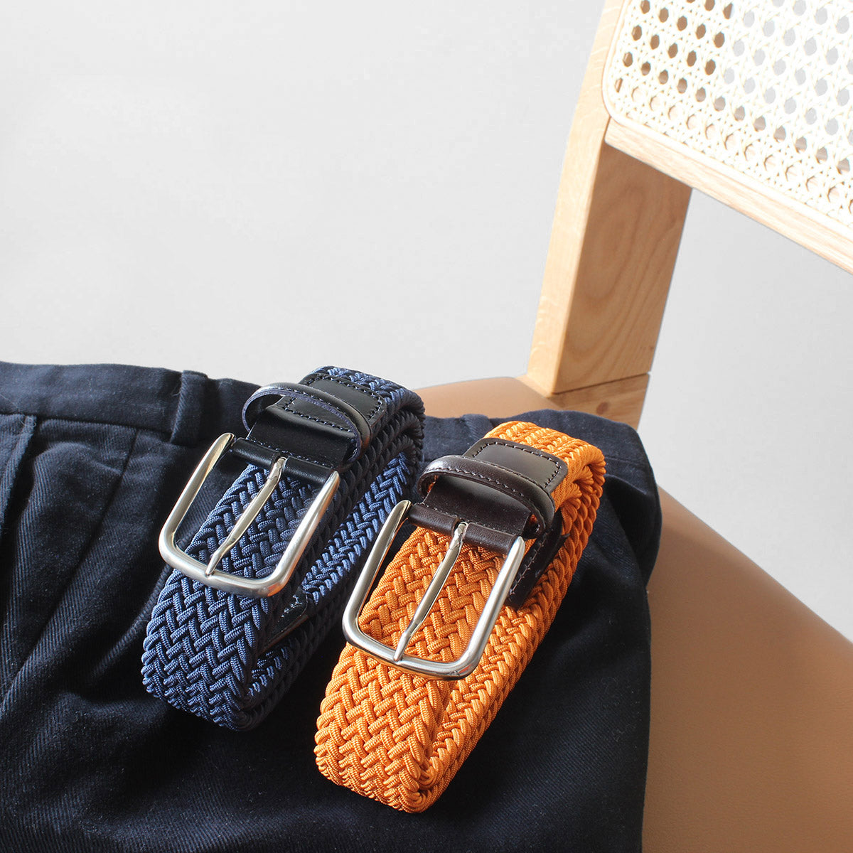 Navy and orange woven elastic belts on navy chinos. Handmade in Italy by Robert Charles.