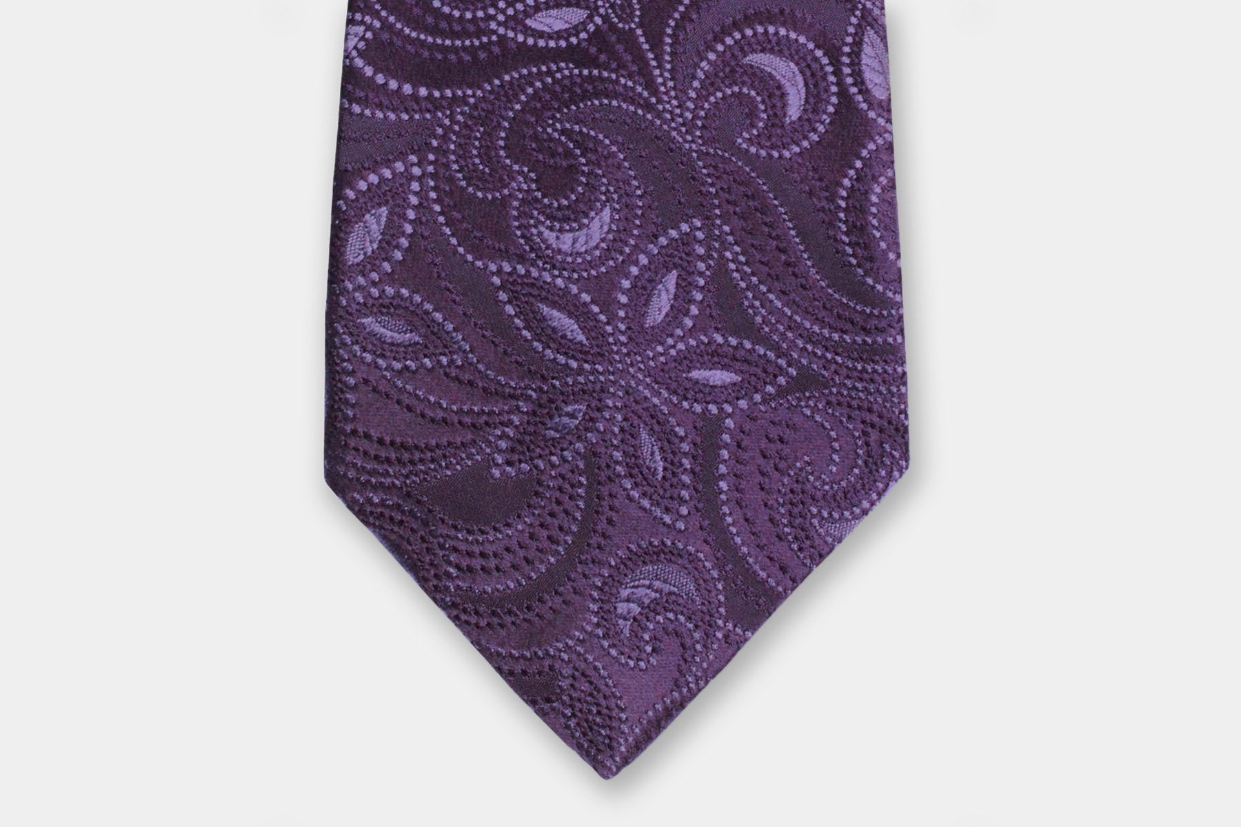 Close-up of a Robert Charles purple silk tie with a paisly design showcasing the artisan Italian intricate weave.