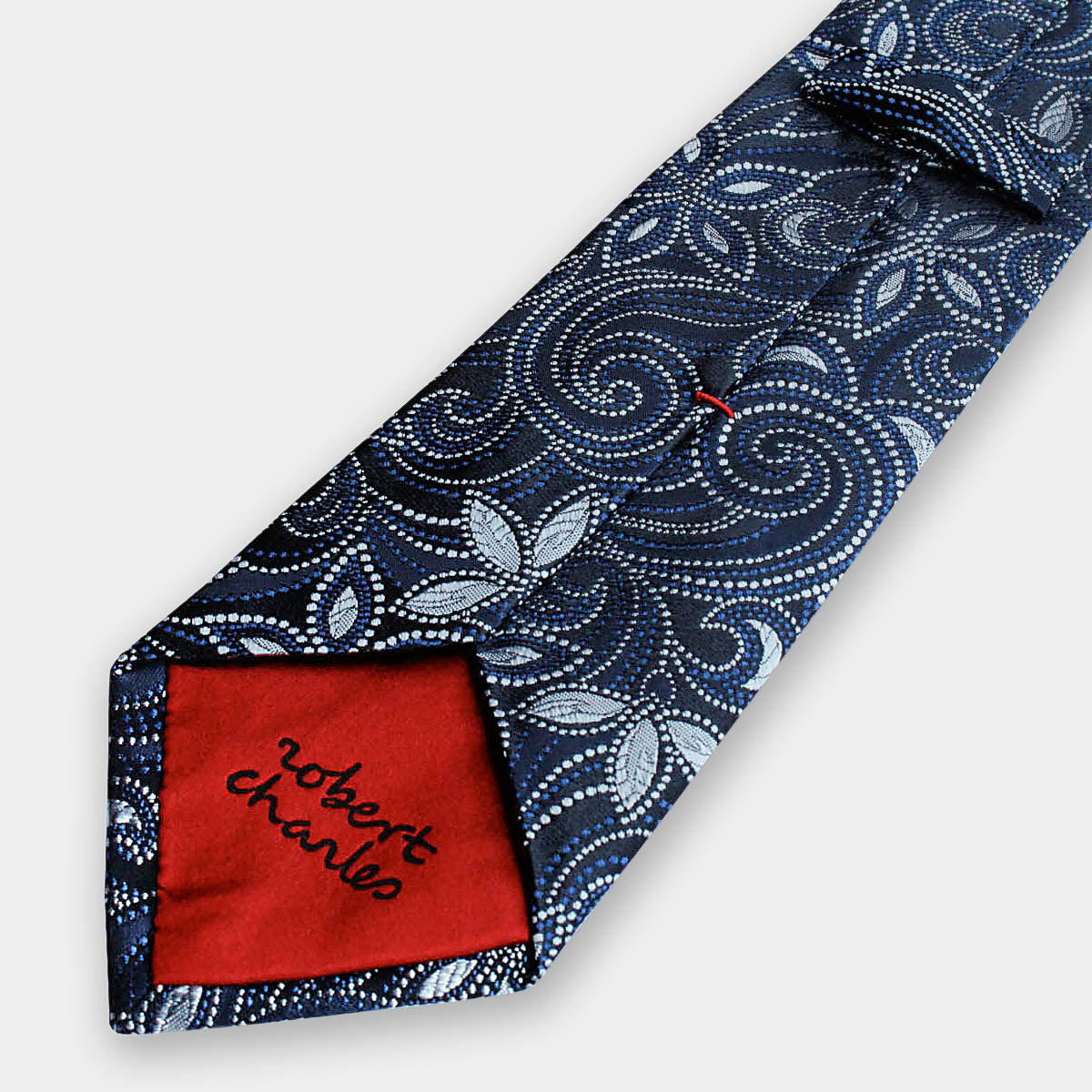 Close-up of Robert Charles silk tie tip showcasing hand stitching. Handmade in Italy.