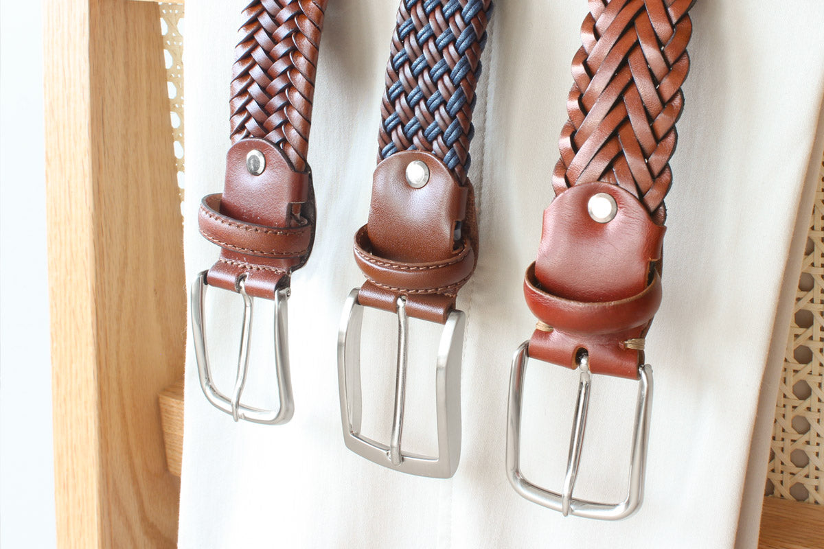 Three brown and navy braided leather belts with silver buckles, showcasing timeless slow fashion craftsmanship.